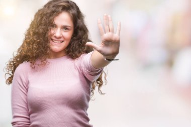 Gösterilen ve parmakları ile işaret izole arka plan üzerinde pembe kazak giyen güzel esmer kıvırcık saçlı Genç kız kendinden emin ve mutlu gülümseyerek süre beş numara.