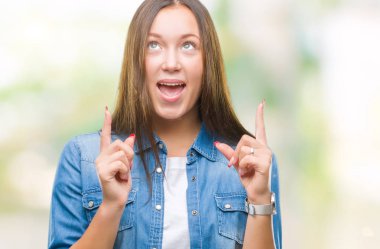 İzole arka plan üzerinde beyaz genç güzel kadın hayrete ve yukarıya bakıyor ve parmakları ile işaret ve silah kaldırdı şaşırttı.