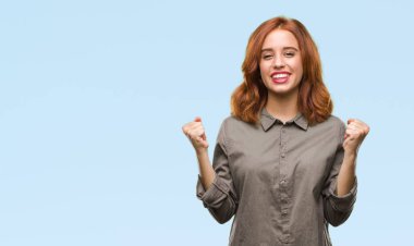 İzole arka plan kutlama üzerinde genç güzel kadın şaşırttı ve başarı için kaldırdı kollarını açarak hayret ve gözleri açık. Kazanan kavramı.