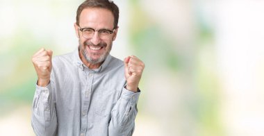 İzole arka plan üzerinde kutluyor gözlük takan yakışıklı orta yaş zarif komuta sizde şaşırttı ve silah ile başarı için yükseltilmiş ve açık gözler hayrete düşürdü. Kazanan kavramı.