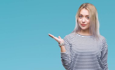 Sarışın genç kadın neşeli sunulması ve kameraya bakarak avucunun ile işaret gülümseyen izole arka plan üzerinde.