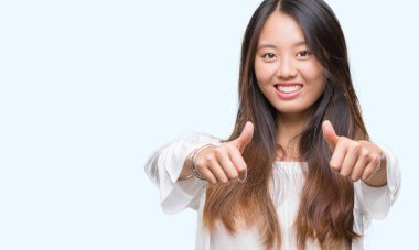 Genç Asyalı kadın el ile pozitif jest yapıyor onaylama izole arka plan üzerinde başparmak gülümseyen ve başarı için mutlu. Kamera, kazanan jest arıyorsunuz.