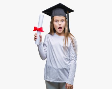 Genç güzel kız derecesi izole arka plan üzerinde bir sürpriz yüz, korkuyor ve heyecanlı korku ifadesi ile şok korkmuş tutan lisansüstü şapkası