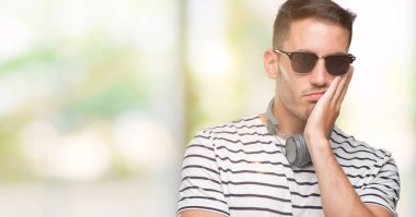 Düşünme seyir yorgun ve depresyon sorunları ile sıkılmış kulaklık takan yakışıklı genç silah geçti.