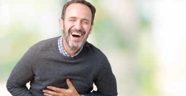 Bir kazak izole üzerinde giyen yakışıklı orta yaş üst düzey adam arka plan gülen ve komik deli şaka çünkü yüksek sesle zor gülüyor. Mutlu ifade.