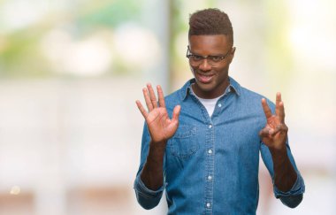 Gösterilen ve parmakları ile işaret izole arka plan üzerinde genç Afro-Amerikan adam kendinden emin ve mutlu gülümseyerek süre sekiz numara.
