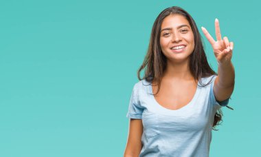 Genç güzel Arap kadın mutlu yüz zafer işareti yaparken kameraya göz kırpıyor ile gülümseyen izole arka plan yüzünden. İki numaralı.