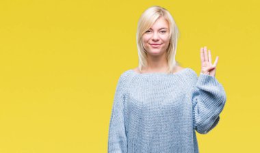 Genç güzel sarışın kadın giyiyor kış kazak gösterilen ve parmakları ile işaret izole arka plan üzerinde dört kendinden emin ve mutlu gülümseyerek iken numara.