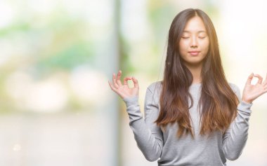 Genç Asyalı kadın izole arka plan üzerinde dinlenmek ve gülümseyen gözlerle parmak ile meditasyon jest yapıyor kapalı. Yoga kavramı.