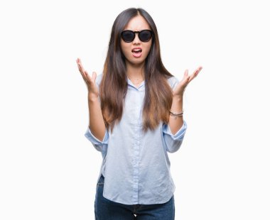 Genç Asyalı kadın üzerinde güneş gözlüğü takıyor arka plan deli izole ve deli bağırarak ve agresif ifade ve silah kaldırdı bağırıyor. Hayal kırıklığı kavramı.