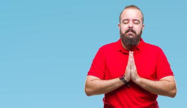 Ellerle birlikte AF emin gülümseyen için soran dua izole arka plan üzerinde kırmızı gömlek giymiş genç beyaz hipster adam.