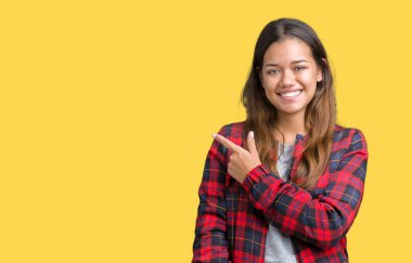 İzole arka neşeli bir gülümseme ile el ve parmak kadar yan yüzünde mutlu ve doğal ifade ile işaret yüz üzerinden bir ceket giyen genç güzel esmer kadın