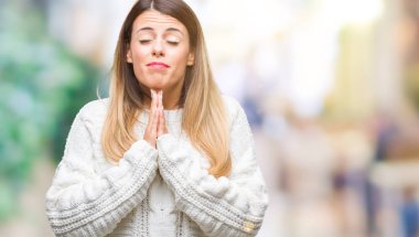 Genç güzel kadın rahat beyaz kazak yalvarıyor ve umut ifade yüzünde çok duygusal ve endişe ile birlikte elleriyle dua izole arka plan üzerinde. Bağışlanmak. Din kavramı.