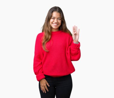 Kırmızı kış kazak izole arka plan Waiving mutlu selam söyleyerek üzerinde ve gülümseyen, dostça karşılama jest giyen genç güzel esmer kadın