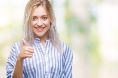 Genç Sarışın kadın hareketi el ile mutlu yaşasın yapıyor izole arka plan yüzünden. Kameraya bakarak başarı gösteren ile ifade onaylama.