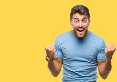 İzole arka plan kutlama üzerinde genç yakışıklı adam şaşırttı ve başarı için kaldırdı kollarını açarak hayret ve gözleri açık. Kazanan kavramı.