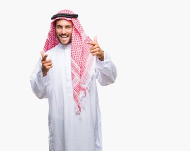 Keffiyeh fotoğraf makinesi ile mutlu ve komik yüz için parmakları işaret izole arka plan üzerinde giyen genç yakışıklı adam. İyi enerji ve vibes.