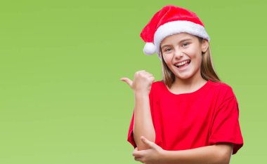 Seyir ve başparmak yanında yukarıyı mutlu yüz ile gülümseyen izole arka plan üzerinde Noel şapka giyen genç güzel kız.