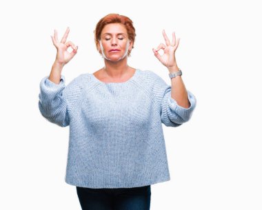 Atrractive üst düzey beyaz Kızıl saçlı kadın giyiyor kış kazak izole arka plan üzerinde dinlenmek ve gülümseyen gözlerle kapalı parmak jestle meditasyon yapıyor. Yoga kavramı.