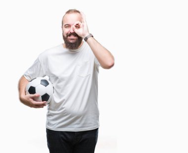 Mutlu yüz el parmaklarının arasından seyir göz üzerinde ok işaretiyle yapıyor gülümseyen izole arka plan üzerinde futbol futbol topu tutan genç beyaz hipster adam