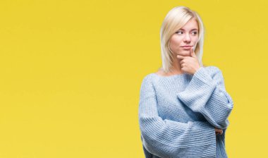 Çene düşünme hakkında soru, dalgın ifade üzerine el ile izole arka plan üzerinde kış kazak giyen genç güzel sarışın kadın. Düşünceli yüzüyle gülümsüyor. Şüphe kavramı.