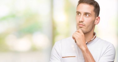 Yakışıklı genç casual adam giyen beyaz t-shirt ciddi bir yüz düşünme çok soru hakkında fikir karıştı