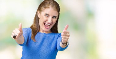 El ile pozitif jest yapıyor onaylama izole arka plan üzerinde kış kazak giyen güzel orta yaş Olgun kadın başparmak gülümseyen ve başarı için mutlu. Kamera, kazanan jest arıyorsunuz.