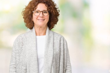 Güzel orta ager üst düzey kadın üzerine ceket ve gözlük takıyor arka yüzünde mutlu ve güzel bir gülümseme ile izole. Şanslı kişi.