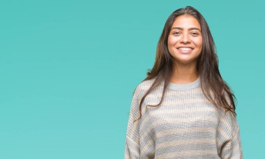 Yüzünde mutlu ve güzel bir gülümseme ile izole arka plan üzerinde kış kazak giyen genç güzel Arap kadın. Şanslı kişi.