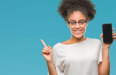Genç güzel afro Amerikan smartphone ekran üzerinde gösterilen arka plan el ve parmak ile tarafına işaret çok mutlu izole.