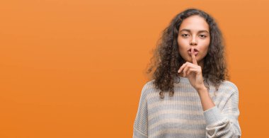 Dudaklarında parmak ile sessiz olmanı çizgili süveter giyen güzel genç İspanyol kadın. Sessizlik ve gizli kavramı.