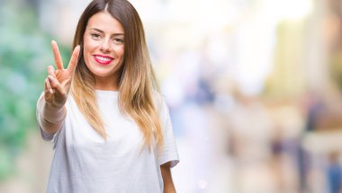 Genç güzel kadın rahat beyaz t-shirt gösterilen ve parmakları ile işaret izole arka plan üzerine ikinci gülümseyen ise kendinden emin ve mutlu.