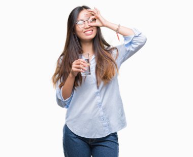 Genç Asyalı kadın ile mutlu yüz el parmaklarının arasından seyir göz üzerinde ok işaretiyle yapıyor gülümseyen izole arka plan üzerinde bir bardak su içme