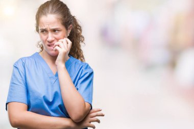 Stresli ve gergin elle çivi ısırma ağzına bakarak izole arka plan üzerinde hemşire ya da cerrah üniforma giyen genç esmer doktor kız. Anksiyete sorunu.