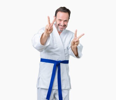 Yakışıklı orta yaş üst düzey zafer işareti yapıyor parmak gösterilen kamera seyir gülümseyen izole arka plan üzerinde kimono üniforma giyen adam. İki numaralı.