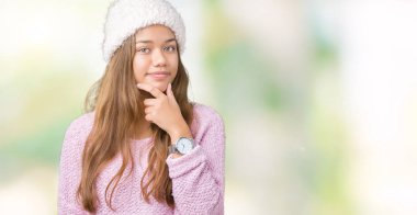 Kazak ve izole arka plan seyir üzerinde kış şapka kendinden emin çapraz kollar ve çeneme kaldırdı el ile gülümseme ile kameraya giyen genç güzel esmer kadın. Pozitif düşünce.