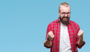 Üzerinde gözlük takan Genç beyaz hipster adam arka plan çok mutlu ve heyecanlı kaldırdı, silah ile kazanan jest yapıyor gülümseyen ve başarı için çığlık izole. Kutlama kavramı.