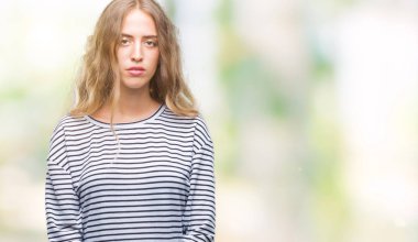 Üzerinde çizgili süveter giyen güzel genç sarışın kadın arka yüzünde ciddi bir ifade ile izole. Basit ve doğal kameraya bakıyor.