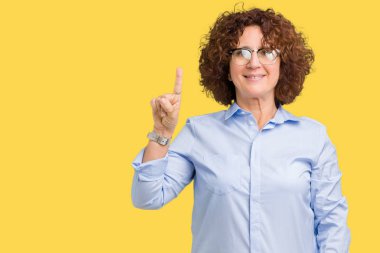 Ve kendinden emin ve mutlu gülümseyerek süre parmak numaralı yukarıyı gösteren izole arka plan üzerinde gözlük güzel orta ager üst düzey businees kadın.