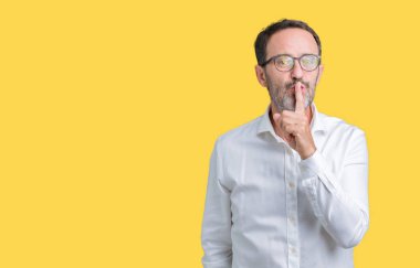 Dudaklarında parmak ile sessiz olmanı izole arka plan üzerinde gözlük takan yakışıklı orta yaş zarif üst düzey iş adamı. Sessizlik ve gizli kavramı.