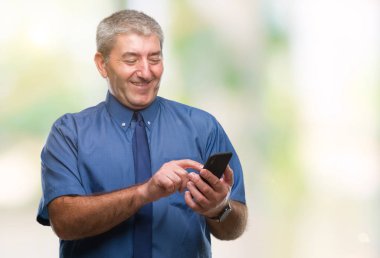 Yakışıklı komuta sizde manifatura izole arka plan üzerinde duran ve diş gösterilen kendine güvenen bir gülümsemeyle gülümseyerek mutlu bir yüz ile Smartphone kullanarak ileti gönderme