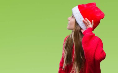 Genç güzel kız bir işitme söylenti ya da dedikodu için dinleme kulak üzerinde el ile gülümseyen izole arka plan üzerinde Noel şapka giyiyor. Sağırlık kavramı.