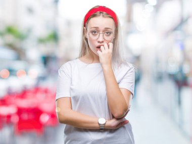 Stresli ve gergin elle çivi ısırma ağzına bakarak izole arka plan üzerinde gözlüklü sarışın genç kadın. Anksiyete sorunu.