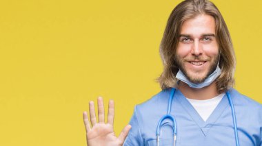 Üzerinde uzun saçlı Genç yakışıklı Doktor adam arka plan gösteren izole ve parmakları ile işaret numara 9 kendinden emin ve mutlu gülümseyerek süre.