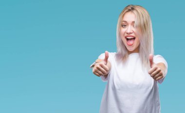 İzole edilmiş bir geçmişi olan genç sarışın kadın elleriyle olumlu bir jest yapmayı onaylıyor. Gülümsüyor ve başarı için seviniyor. Kameraya bak, kazanan jest..