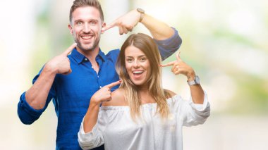 Kendinden emin gösterilen ve işaret parmakları diş ve ağız ile gülümseyen izole arka plan üzerinde aşık genç bir çift. Sağlık kavramı.