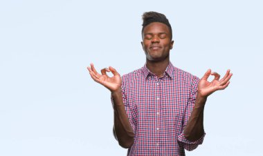 Genç Afro-Amerikan adam izole arka plan üzerinde dinlenmek ve gülümseyen gözlerle parmak ile meditasyon jest yapıyor kapalı. Yoga kavramı.