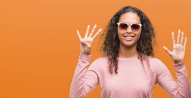 Güzel genç İspanyol kadın ve parmak dokuz ile gülümseyen ise kendinden emin ve mutlu yukarıyı gösteren güneş gözlüğü takıyor.