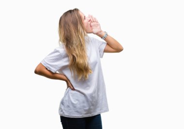 Bağırarak ve ağzı üzerinde el ile yan için çığlık izole arka plan üzerinde rahat beyaz t-shirt giyen genç güzel sarışın bir kadın. İletişim kavramı.