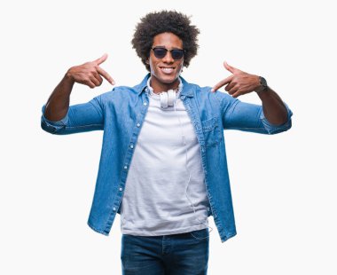 Yüzünde gülümseme ile kendinden emin görünüyorsun, kendini gururlu ve mutlu parmakları ile işaret izole arka plan üzerinde müzik kulaklık giyen Afro Amerikalı adam.